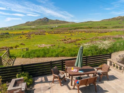 a patio with a table and a umbrella and chairs at Carn Llidi Cottage in St. Davids