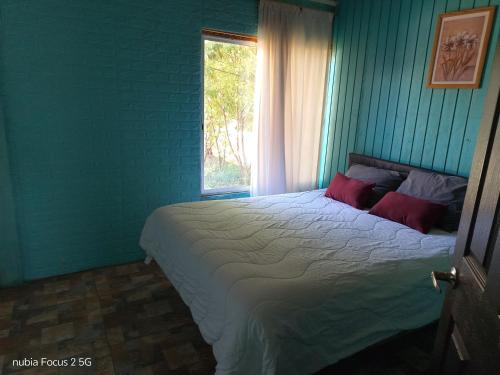 Un dormitorio con una cama grande con ventana. en Cabaña Azul, en Vallenar