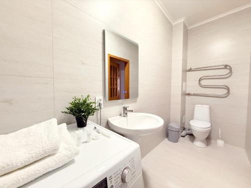 une salle de bain blanche avec un lavabo et des toilettes dans l'établissement Keruen shopping mall, Abu Dhabi Plaza shopping mall, Baiterek, à Astana