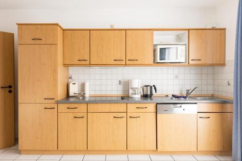 a kitchen with wooden cabinets and a microwave at Inselglück App 2 in Norderney