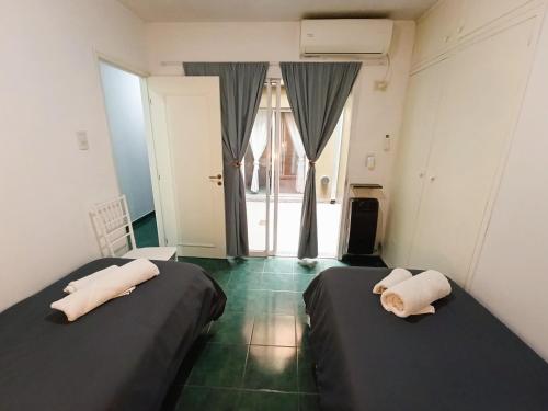 two beds in a room with a window at Amplio departamento en pleno centro con cochera privada in San Rafael