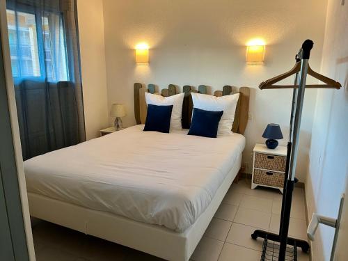 una camera da letto con un grande letto bianco con cuscini blu di Appartement Miramar a Banyuls-sur-Mer