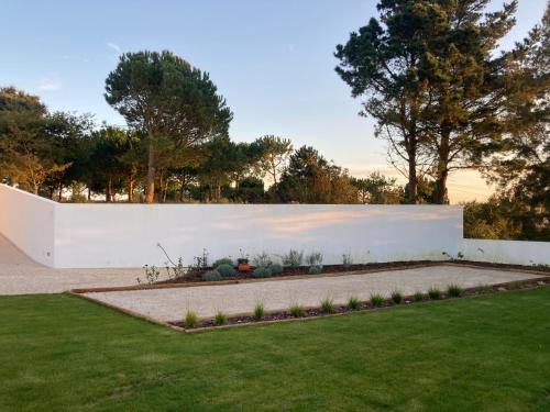 a garden with a white wall and a lawn at Ikigai B&B in Carvalhal
