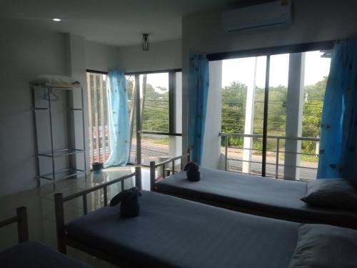 two beds in a room with a large window at มังกรเลโฮลเทลกระบี่ Mangkonlay Hostel Krabi in Ban Khlong Chi Lat