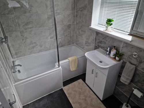 een badkamer met een wit bad en een wastafel bij Relaxing House in Hull