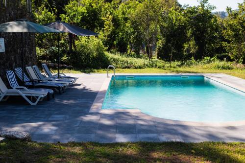 a swimming pool with two chairs and an umbrella at Quinta do Assento in Louredo