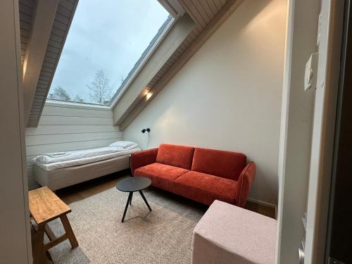 a living room with a red couch and a window at Naava Chalet Penthouse - Kattohuoneisto järvinäköalalla in Ähtäri
