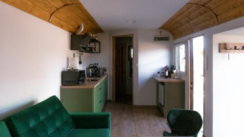 a living room with a green couch and a kitchen at Magiczny Widok Tiny House in Jurków