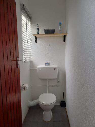 a bathroom with a toilet and a shelf on the wall at Cozy Cove in Cape Town