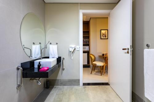 a bathroom with a sink and a mirror at Vilinha típica - Suíte Onze Tuin - Entrada com senha - Somos hospedagem por temporada in Holambra