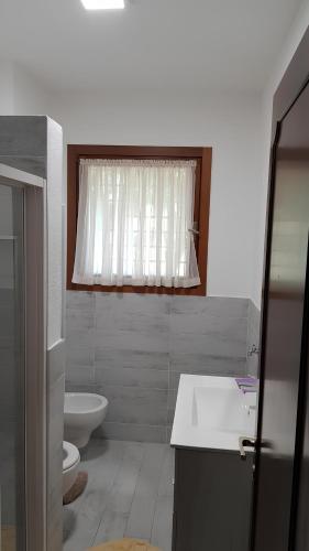 a bathroom with a sink and a toilet and a window at Appartamento in residence con piscina in Luino