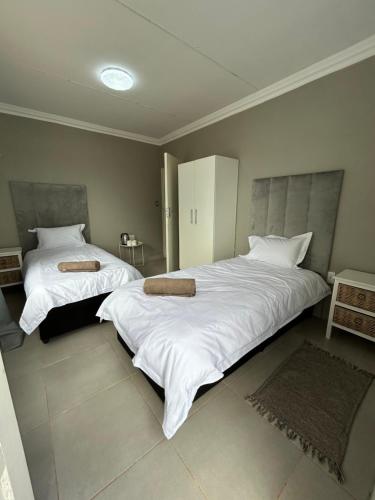 two beds in a bedroom with white sheets and pillows at Riverview Pool Resort and Lodge in Moletlane