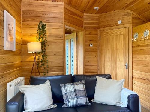 een zwarte leren bank in een kamer met houten wanden bij Maple - Uk46284 in Camerton