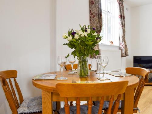 une table avec un vase de fleurs et des verres à vin dans l'établissement Fallow Cottage - Uk33488, à Hadleigh