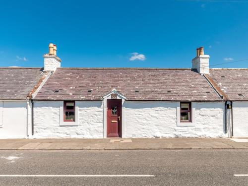 a white building with a red door on a street at Drumwherry By The Sea in Monreith