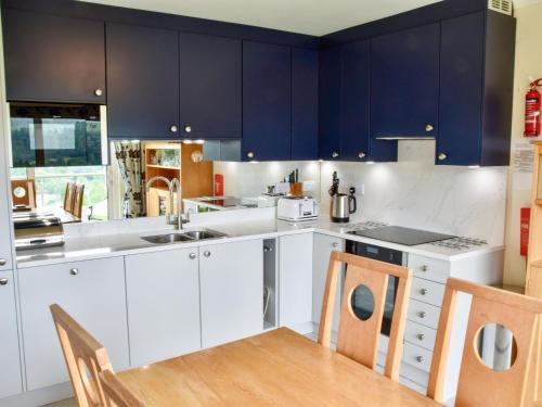 a kitchen with blue cabinets and a wooden table at Badgers Rake 12 Squirrels Nest in Ambleside