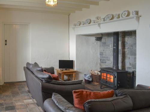 a living room with leather couches and a fireplace at Penrhyn Mawr - Hw7642 in Aberdaron