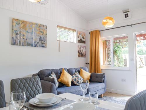 ein Wohnzimmer mit Sofa und Tisch in der Unterkunft The Lodge At Forbury Cottage in Kimbolton