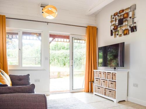 ein Wohnzimmer mit Sofa und Fernseher in der Unterkunft The Lodge At Forbury Cottage in Kimbolton