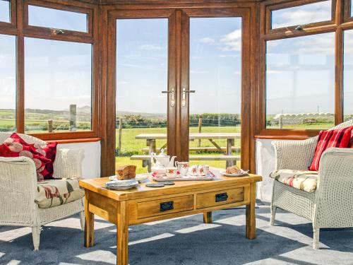 - un salon avec une table basse et des fenêtres dans l'établissement Beacon Cottage, à Llanrian
