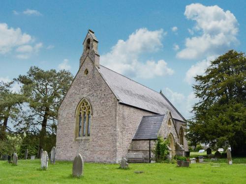 une vieille église en briques avec une tour dans un cimetière dans l'établissement The Bellringers Cottage, à Llandegla