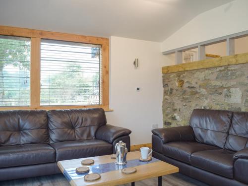 a living room with two leather couches and a coffee table at Llety'r Saer in Pen-y-bont-fawr
