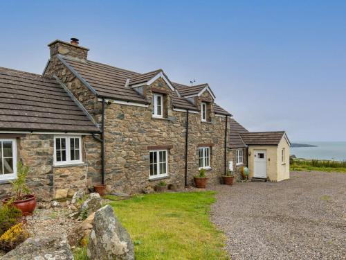 Una antigua casa de piedra con un camino de grava en Penmynydd Uchaf, en Dinas