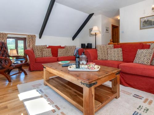 a living room with red couches and a wooden table at Carn Llidi Cottage in St. Davids