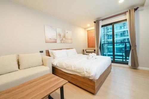 a bedroom with a bed and a couch and a window at New condo near the sea, Laguna, Choeng Thale 324 in Ban Thalat Choeng Thale