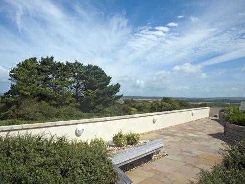 un patio con un banco al lado de una pared en The Sergeants Quarters, Golden Hill Fort, en Freshwater