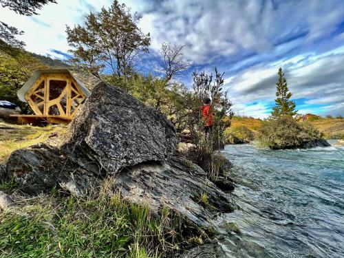 a person standing on a rock next to a river at Surí refugios Aquasol, Carretera Austral, Cochrane in Cochrane