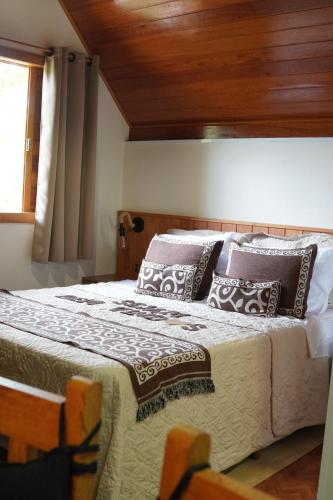 a bedroom with a large bed with pillows on it at Chalé Sognare Due in Santa Teresa