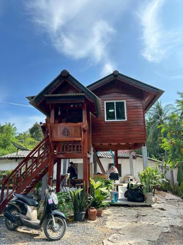 a house with a scooter parked in front of it at Peony brown in Thongsala
