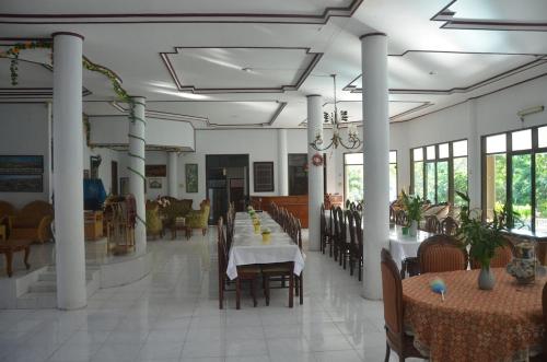 a dining room with tables and chairs and windows at Pondok Ganda in Ambarita