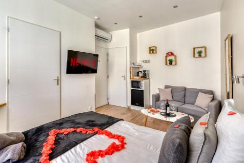 a living room with a couch and a tv at Le Bourget - Envolée Romantique in Narbonne