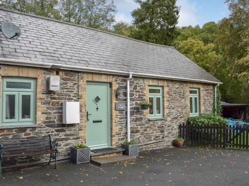 a stone house with a green door and a bench at Ivy Cottage in Henllan