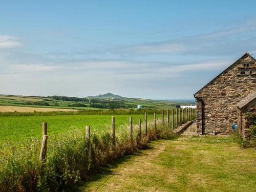 an old stone barn and a fence in a field at The Bickney in Llanrian