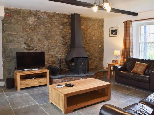 a living room with a stone wall with a fireplace at Acorn Lodge Cottage in Keswick
