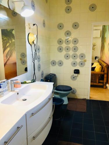 a bathroom with a white sink and a blue toilet at Joli oasis au centre de l'île in Baie-Mahault