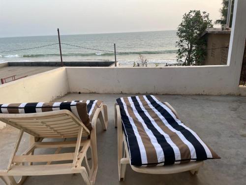 two beach chairs and a pair of towels on a balcony at Lou Fatm' Popenguine in Poponguine