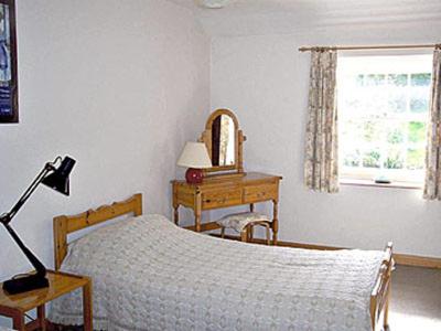 a bedroom with a bed and a table and a mirror at 2 Farfield Cottages in Sedbergh