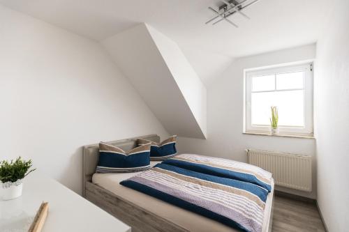 a bedroom with a bed with blue pillows and a window at Inselglück App 4 in Norderney
