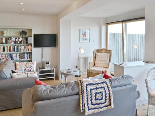 un salon avec un canapé, des chaises et une télévision dans l'établissement Turnstone Cottage, à Sheringham