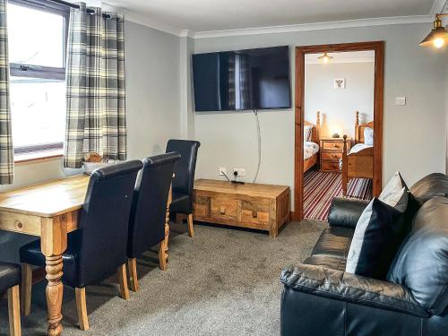 a living room with a wooden table and leather chairs at Haddon Cottage - Uk40270 in Bakewell