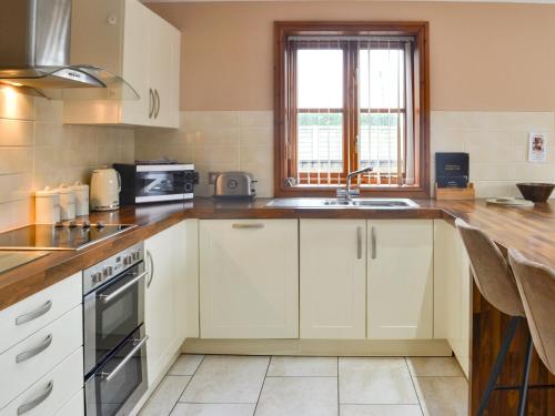a kitchen with white cabinets and a sink at George's Gaff - E4432 in Ingoldmells