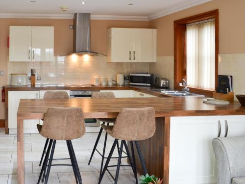 a kitchen with a wooden counter with stools in it at George's Gaff - E4432 in Ingoldmells