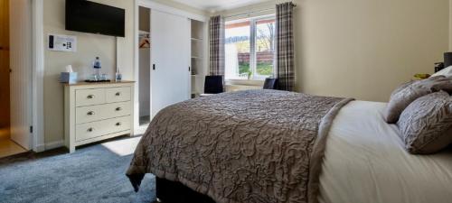 Un dormitorio con una cama y una cómoda con televisión. en Eldon Lea, en Strathpeffer