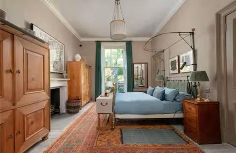 een slaapkamer met een blauw bed en een open haard bij Elegant Georgian Retreat with Views of Arthurs Seat in Edinburgh