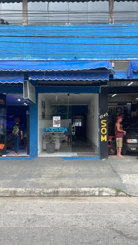 a blue store front with people standing in the window at Hotel Costa Rio - Conforto e Hospitalidade em Rio das ostras in Rio das Ostras