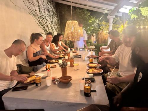 a group of people sitting around a long table with food at Wave Loom Hostel Ahangama in Ahangama